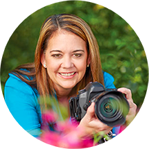 Woman posing in the grass holding a camera